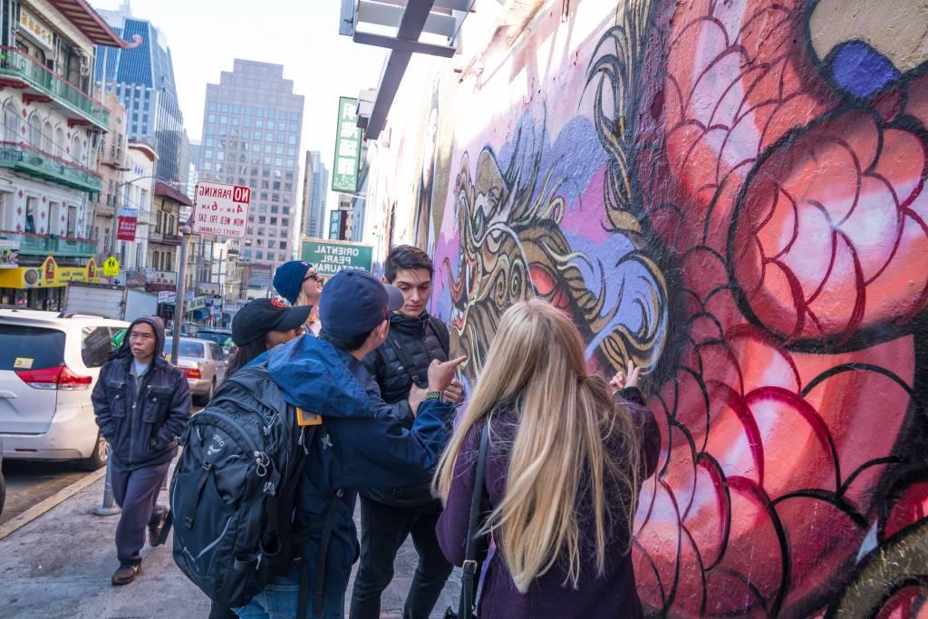 group of people standing next to and talking about a mural