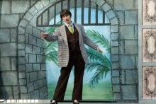 一名男子在城堡大门的彩色背景上伸出手臂，热带植物从大门的入口处窥视着. 