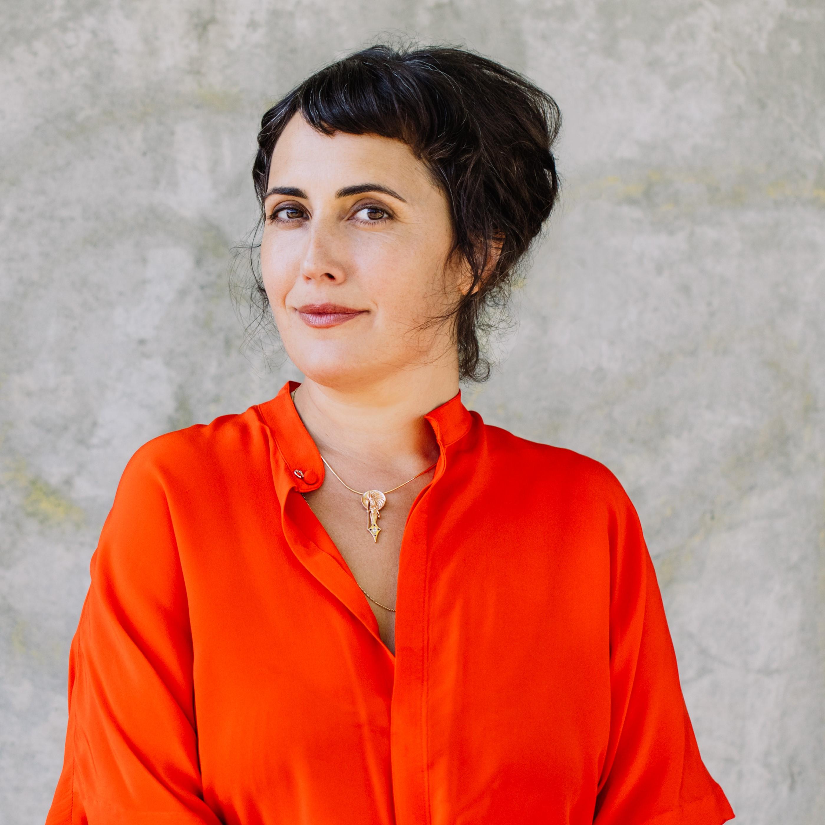 headshot of writer lauren markham in an orange shirt 和 cream background