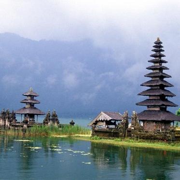 在巴厘岛，以雾和山脉为背景，一个小的水面露出来，一个大的和一个小的寺庙.