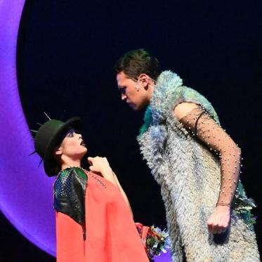 A still from "A Midsummer Night's Dream" with Puck being threatened by another character. 在他们身后，是一轮新月. 