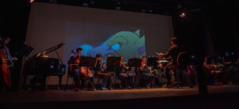 西克托指挥着他的乐队，舞台背景上放映着一部动画电影
