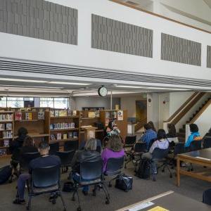 A group of students, faculty, 工作人员聚集在图书馆二楼听诗歌朗诵.