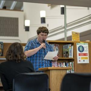 一名身穿蓝色衬衫的学生在“暂停诗歌”上朗读.